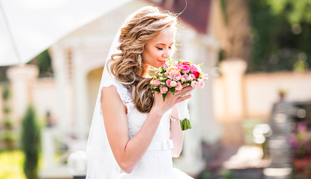 Beautiful bride outdoors in a park with wedding bouquetの写真素材