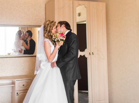 Beautiful wedding couple indoors. They kiss and hug each other.の写真素材