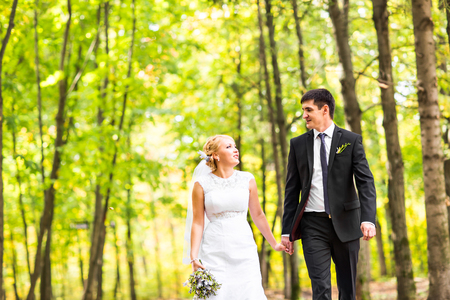 Bride and groom holding hands outdoors in summer parkの写真素材
