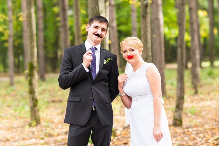 April Fools' Day. Wedding couple posing with stick lips, maskの写真素材