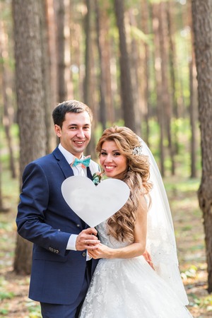 happy Groom and Bride in a park with sign as heart.の写真素材