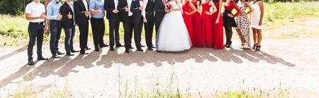 Full length portrait of happy bride and groom standing with guests in gardenの写真素材