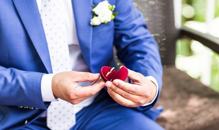 Man's hand holding engagement ring. Wedding rings