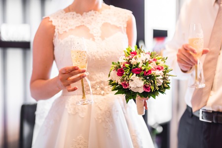 Bride and groom holding wedding champagne glasses.の写真素材