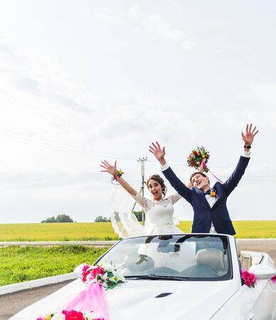 The groom and the bride in a white convertible car.の写真素材