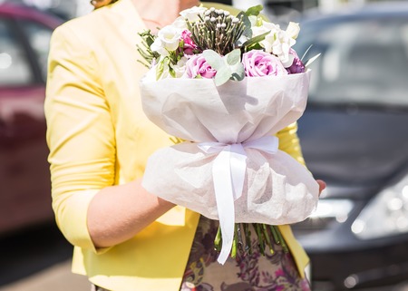 A womans hand is holding a bouquet of flowersの写真素材