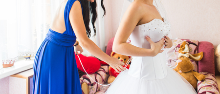 Bridesmaid is helping the bride to dress.の写真素材