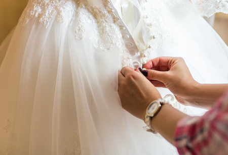 Bridesmaid is helping the bride to dress.の写真素材