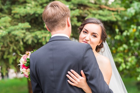 Bride and groom at wedding Day walking Outdoors on spring nature. Bridal couple, Happy Newlywed woman and man embracing in green park. Loving wedding couple outdoor. Bride and groomの写真素材