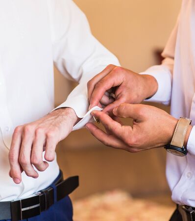Groomsman helps to groom to put on cufflinks