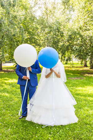 Funny wedding Couple with balloons, standing in a meadow and have funの写真素材