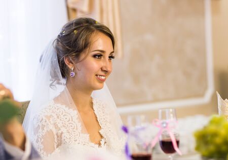 Beautiful bride with fashion wedding hairstyle - on white background.Closeup portrait of young gorgeous bride. Wedding. Studio shot.Beautiful bride portrait with veil over her faceの写真素材