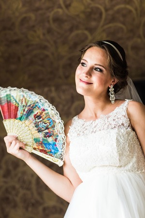 beautiful young bride with a fan indoorsの写真素材