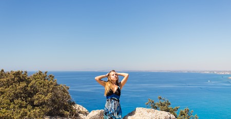 young beautiful caucasian female on a cliff above the sea.の写真素材