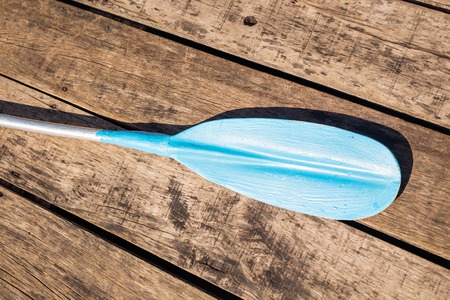 Blue plastic kayak paddle on wooden background.の写真素材