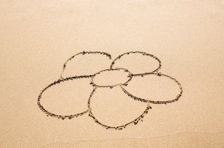 Flower drawn in the sand. simple flower drawing in the sand on the beachの写真素材