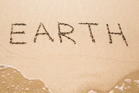 earth text on the sand. handwritten on sandの写真素材