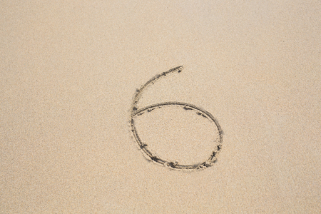 Six number written on sand. Summer beach background.