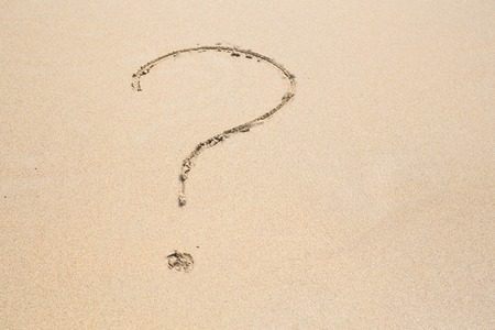 a question mark drawn on the sand of a beachの写真素材