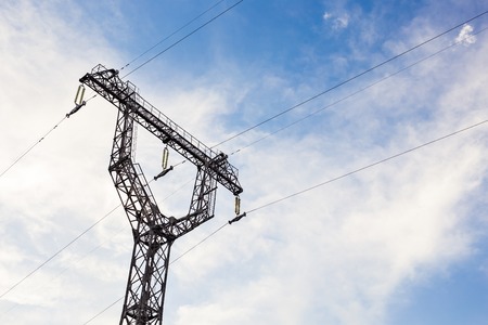 High voltage lines and power pylons on a sunny day with clouds in the blue sky