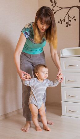 baby steps with the help of his mother.