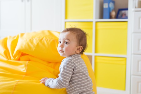 Beautiful adorable laughing baby boy infant face. Smiling child sits on a chairの写真素材