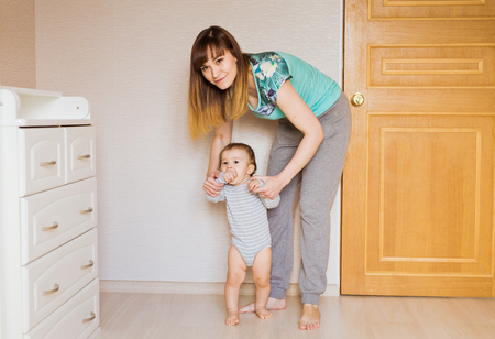little boy first steps with the help of mom.の写真素材