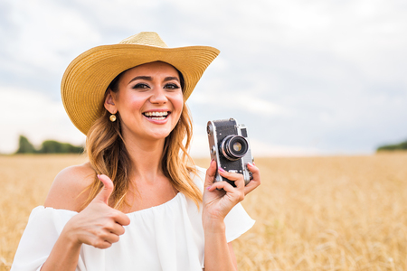 Girl with professional camera giving thumbs up outdoors.の写真素材