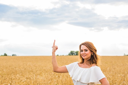 Happy travel woman smile to you and show something by finger with sky background, caucasian beauty.