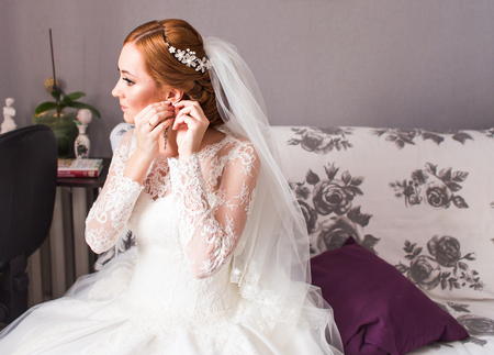 Wedding earrings on a female hand, she takes the earrings, the bride fees, morning bride, white dress, wear earringsの写真素材