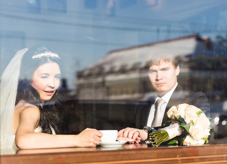 Bride and groom drinking coffee at an indoor cafeの写真素材
