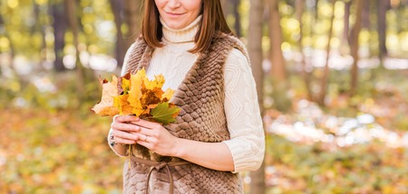 Close-up young woman with maple autumn leaves.