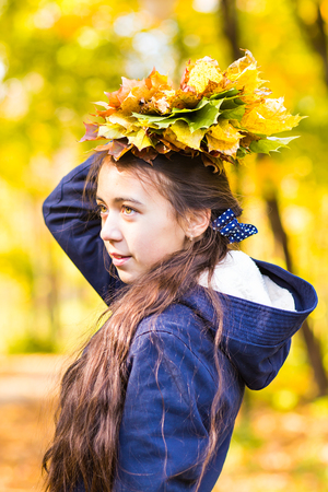 Portrait of young smiling redhead teenage girl holding autumn leaves bouquet. Fall season. Multicolored vibrant outdoors vertical image.の写真素材