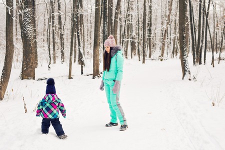 happy mother and baby in winter park. family outdoors. cheerful mommy with her child.の写真素材