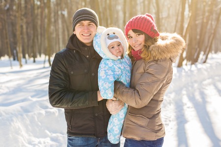 parenthood, fashion, season and people concept - happy family with child in winter clothes outdoors.の写真素材