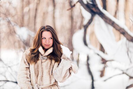 Winter portrait of young beautiful woman wearing fur coat. Snow winter beauty fashion conceptの写真素材