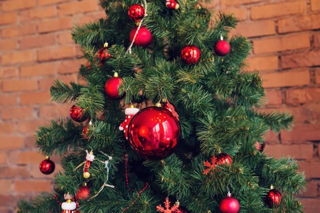 Closeup of red bauble hanging from a decorated Christmas tree