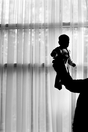 silhouettes of father and little baby playing indoorの写真素材