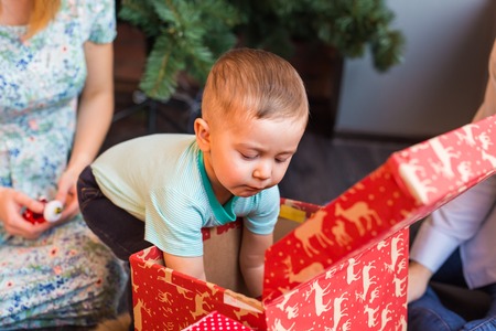 Portrait of adorable boy with giftboxes looking into one of them.の写真素材