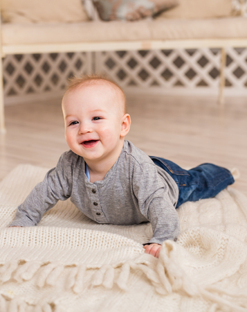 Adorable baby boy in white sunny bedroom. Newborn child relaxing. Family morning at homeの写真素材