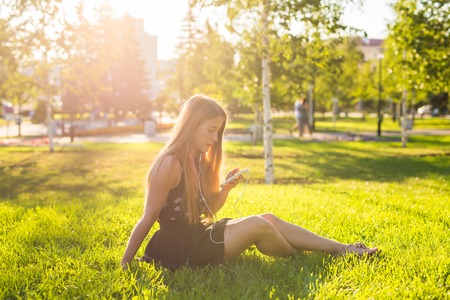 Young woman looking at smartphone and listening music in the parkの写真素材