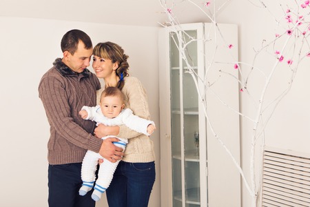 Happy family father, mother and baby boy playing together at home.