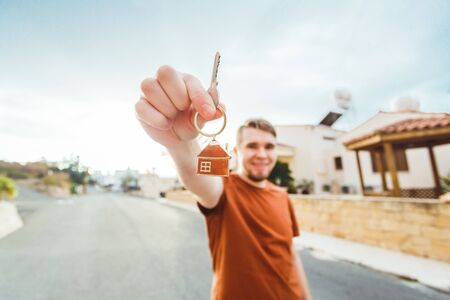 Joyful man shows keys on the background of new homeの写真素材