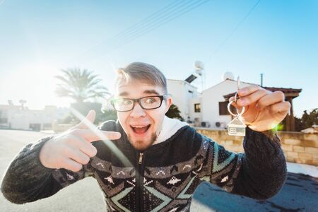 Joyful happy man shows keys on the background of new homeの写真素材