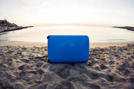 Travel, holiday and vacation concept - blue suitcase on the beach.の写真素材