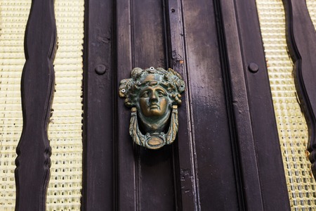 Traditional ornate door handle or knocker against a wooden doorの写真素材