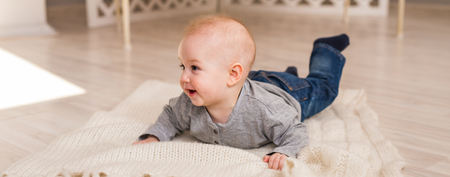 Adorable smiling baby boy in sunny bedroom. Newborn child relaxing. Nursery for young...