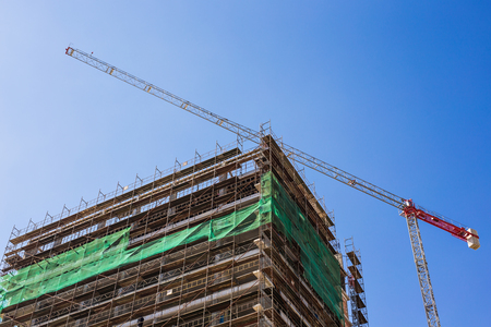 Building crane and building under construction against blue skyの写真素材