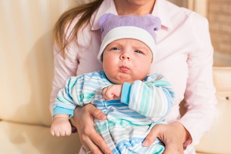 A cute little baby is looking into the camera and is wearing a purpleの写真素材