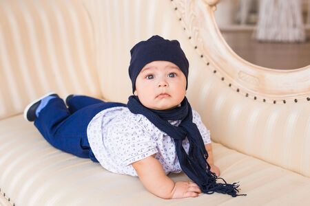 Adorable baby boy in the room. Newborn child relaxing on the couch. Nursery for young children. Family morning at home.の写真素材